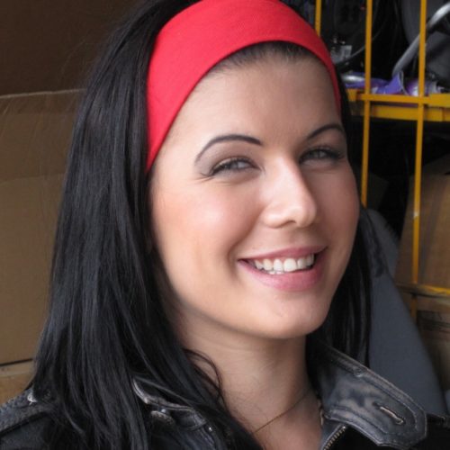 Portrait d'une femme brune et souriante avec un bandeau rouge dans les cheveux