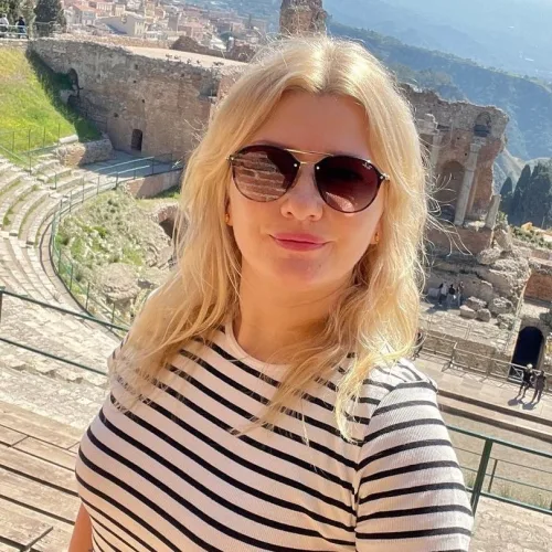 Une belle blonde porte des lunettes de soleil elle fait un selfie devant des ruines antiques