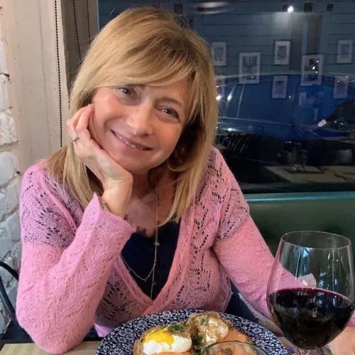 Belle femme mature souriante à table devant un verre de vin