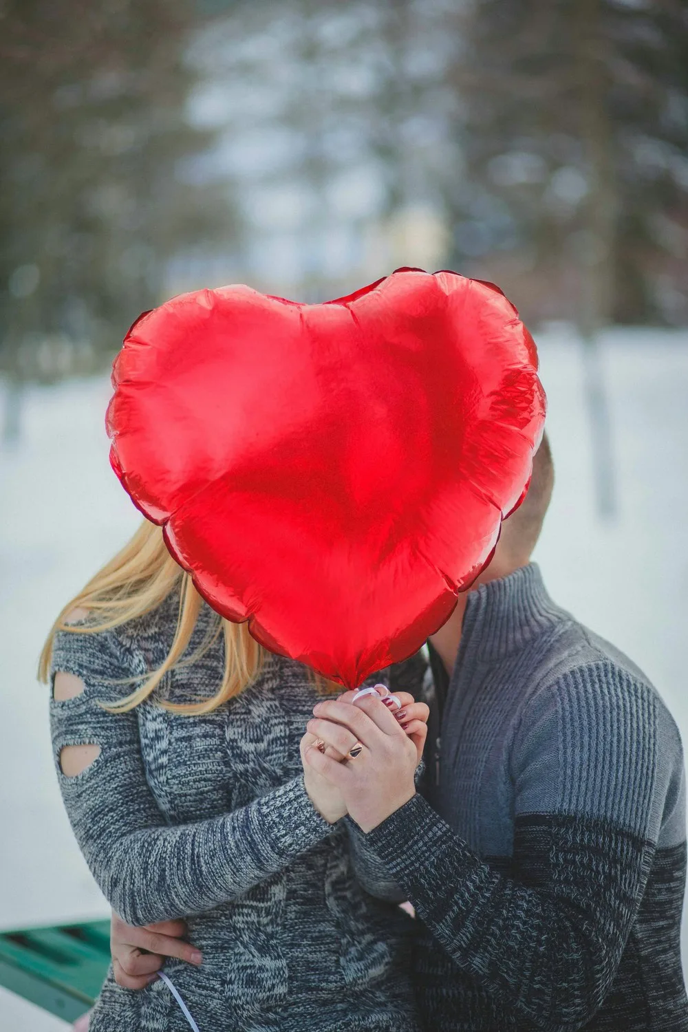 Un cœur en ballon gonflable rouge cache un couple d'amoureux.